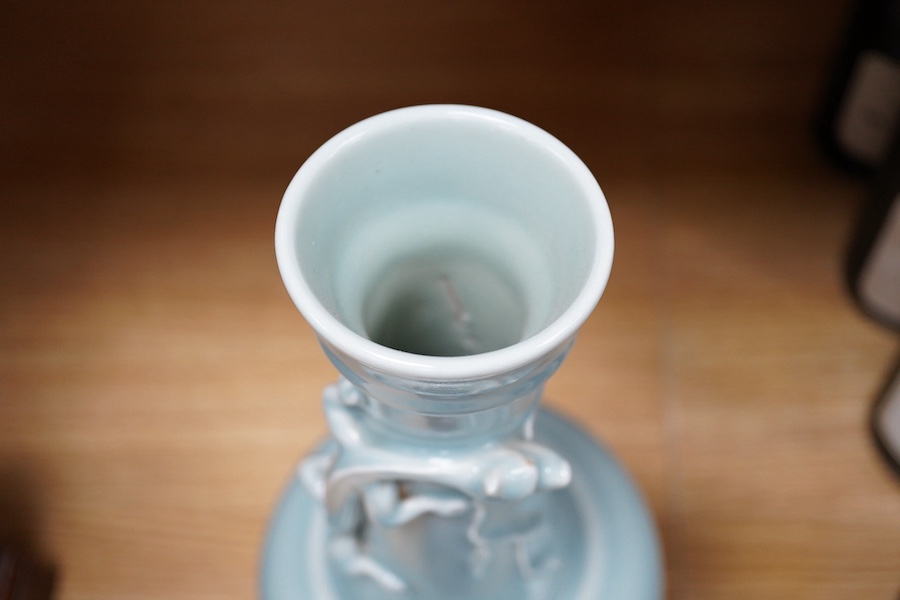 A Chinese celadon glazed vase, 20th century, decorated in relief with a dragon, with an associated hardwood stand, 37cm high. Condition - good